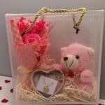 Ροζ gift box Αγίου Βαλεντίνου με ροζ αρκουδάκι, τεχνητή ανθοδέσμη και χρυσό ατσάλινο κολιέ 45 cm σε διάφανο κουτί με χερούλι